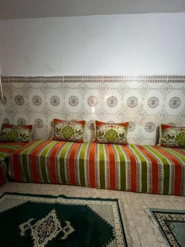 a living room with two beds and a wall at Maison Ghali in Safi