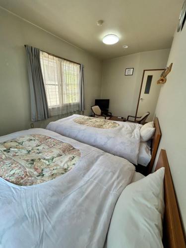 a bedroom with two beds and a window at トガリハイランド白樺 in Iiyama