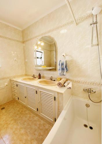 a bathroom with a tub and a sink and a mirror at VilaMar in Salema