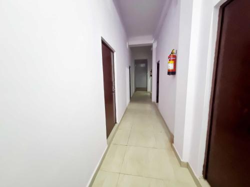 un pasillo vacío con paredes blancas y un largo pasillo en OYO 90856 HOTEL MANNAT, en Aligarh
