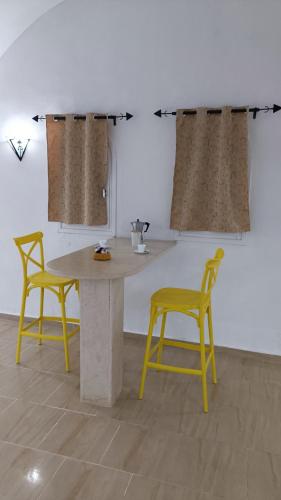a table and two yellow chairs in a room at Maison Sérénité Campagne in Hammamet Sud