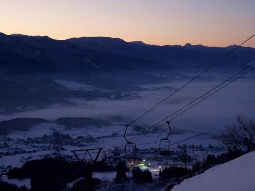 a ski lift on a snowy mountain at sunset at トガリハイランド白樺 in Iiyama