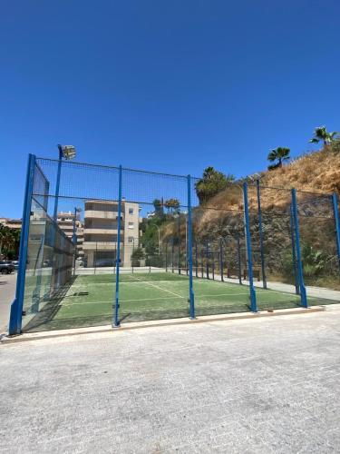 a tennis court behind a fence in a field at Benalmadena Suite Vistas panorámicas, 2 piscinas, Area infantil, Bar, Jardines y Tenis in Benalmádena
