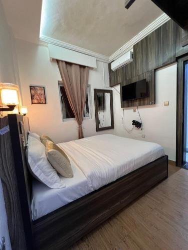 a bedroom with a large white bed with a television at Amelia Aparthotel in Buea