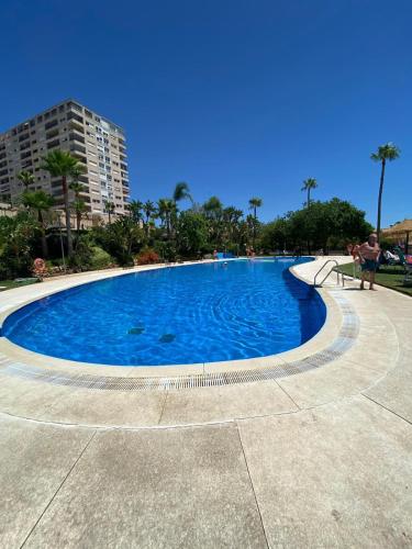 a large swimming pool with blue water at Benalmadena Suite Vistas panorámicas, 2 piscinas, Area infantil, Bar, Jardines y Tenis in Benalmádena