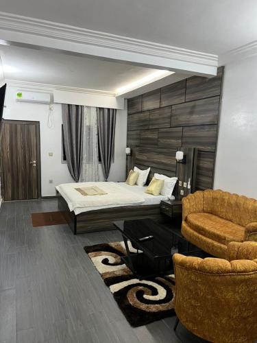 a bedroom with a bed and a couch and a chair at Amelia Aparthotel in Buea
