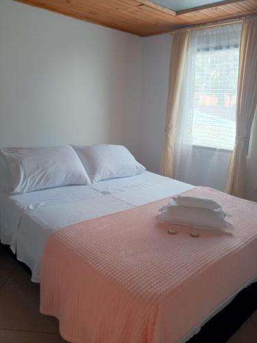 a bedroom with a bed with white sheets and a window at Hotel El Balcon de madera in Norcasia