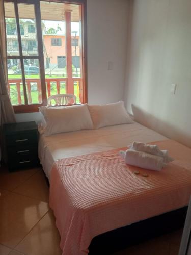 a bed with two towels on it in a room with a window at Hotel El Balcon de madera in Norcasia