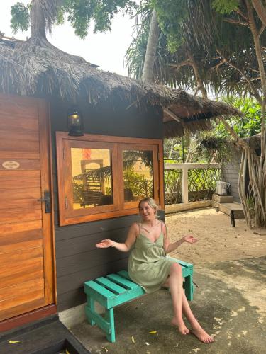 a woman sitting on a bench in front of a hut at Tomorrowland Beach Villas in Tangalle