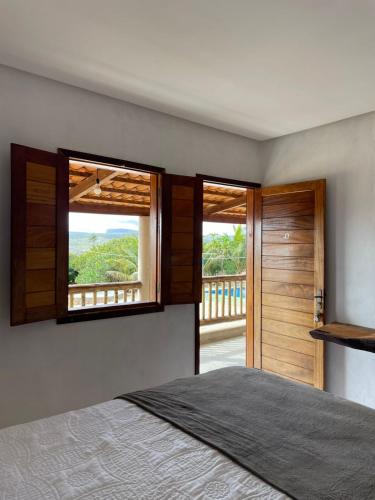 a bedroom with a bed and two windows and a balcony at Hotel Fazenda Brisa dos Gerais in Palmeiras