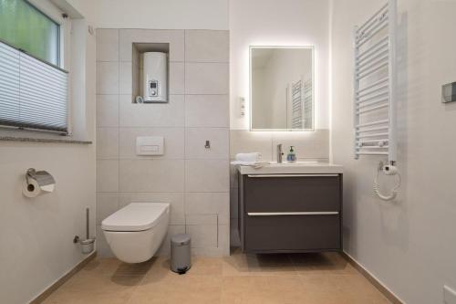 a white bathroom with a toilet and a sink at Ferienhaus-Anton-Charlotte in Schwarz