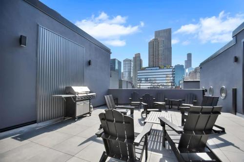 a patio with chairs and a grill on a rooftop at River North Private Balcony With In and Out Parking in Chicago
