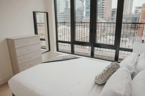 a bedroom with a white bed and large windows at River North Private Balcony With In and Out Parking in Chicago