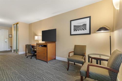 a hotel room with a desk and a tv and chairs at Best Western Plus Stevenson Manor in Calistoga