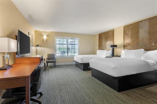 a hotel room with two beds and a desk at Best Western Plus Stevenson Manor in Calistoga