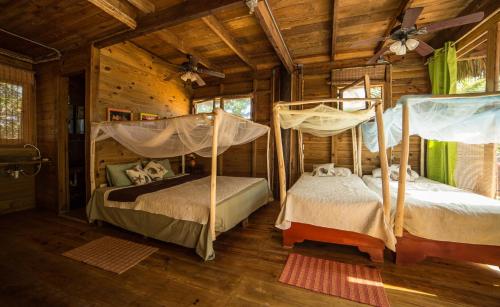 two beds in a room in a log cabin at Cabarete Ecolodge Encuentro Surf Beach Kite in Perla Marina by BTCG Crypto in Bombita