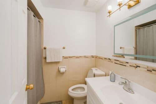 a bathroom with a sink and a toilet and a mirror at Newly Renovated 3BR North York Bungalow with Backyard Patio & Volleyball Set! Close to Rogers Stadium, TTC Subway Access, Perfect for Family Travel, Group Trips or Work Stays! in Toronto