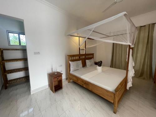 a bedroom with a canopy bed and a night stand at Zanzibar beach escape 1&2 in Bwejuu