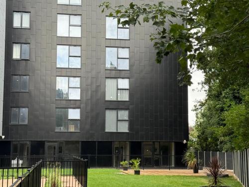 a tall black building with a grass field in front of it at Quality City Green Luxury Apts Close to NEC & Airport in Birmingham