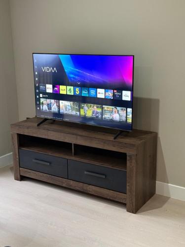 a flat screen tv sitting on top of a wooden stand at Quality City Green Luxury Apts Close to NEC & Airport in Birmingham