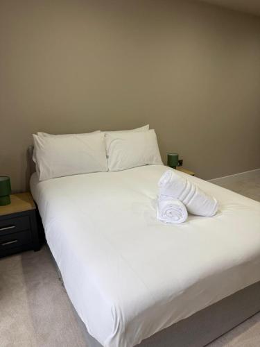 a large white bed with a towel on it at Quality City Green Luxury Apts Close to NEC & Airport in Birmingham