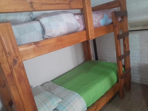 a wooden bunk bed with a green bottom bunk at Cabaña Mariza in Trapiche