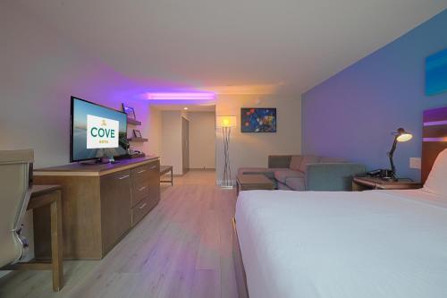 a hotel room with a bed and a flat screen tv at The Cove Hotel in Long Beach