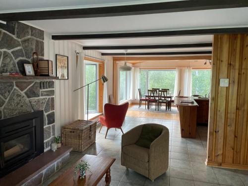 een woonkamer met een stenen open haard en een stoel bij Le Refuge des Eaux Vives in La Macaza