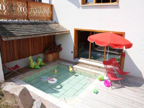 a patio with two chairs and a red umbrella at Rustic Chalet for Families in Le Ménil