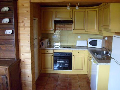 a kitchen with yellow cabinets and a stove top oven at Rustic Chalet for Families in Le Ménil