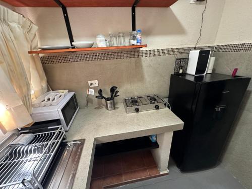 Una pequeña cocina con estufa y refrigerador. en Peach35L Céntrico studio super ubicado y tranquilo, en Cancún