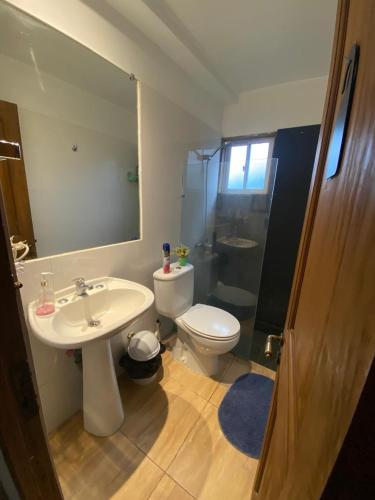a bathroom with a sink and a toilet and a mirror at Casa lago rapel in Lago Rapel
