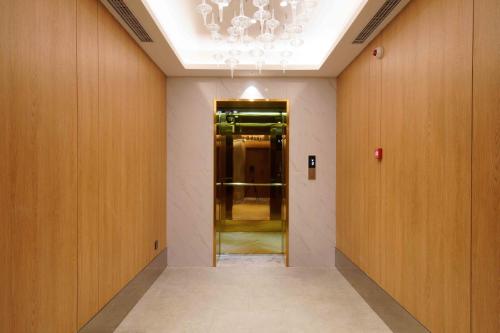 a hallway with a chandelier and a hallway with a door at Orange Beijing Yanqing Badaling Great Wall Hotel in Xibozi