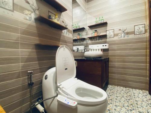 a bathroom with a white toilet and a sink at Nhà Gỗ Chân Nguyên Villa in Ấp Ða Lôc