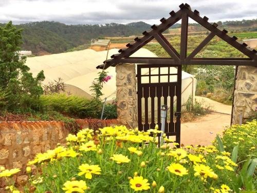 a gate in a garden with yellow flowers at Nhà Gỗ Chân Nguyên Villa in Ấp Ða Lôc