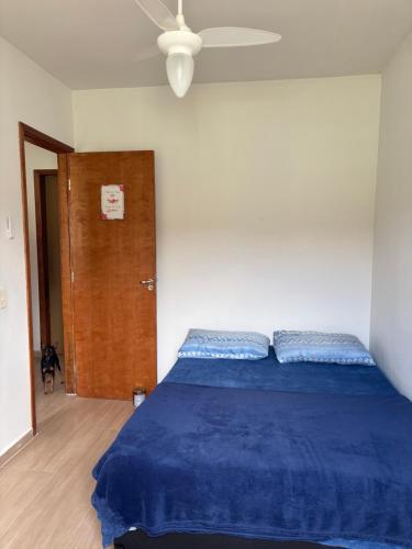 a bedroom with a blue bed and a wooden door at Casa Temporada Itanhaém Portaria 24h in Itanhaém