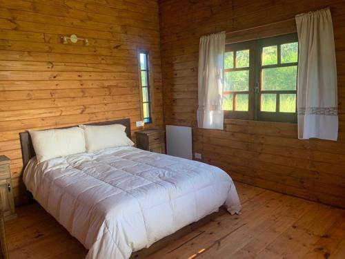 Un dormitorio con una cama en una cabaña de troncos en La Presumida, en Baradero