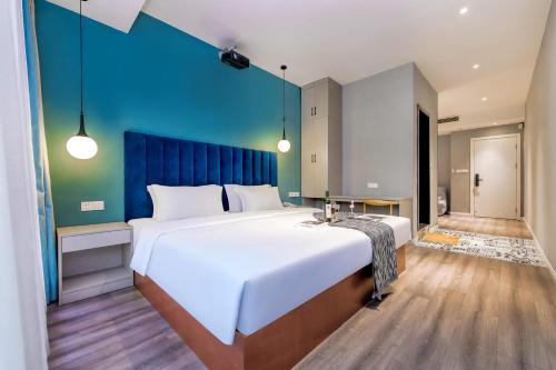 a large bed in a room with a blue wall at 重庆莎霏酒店大渡口店 in Chongqing