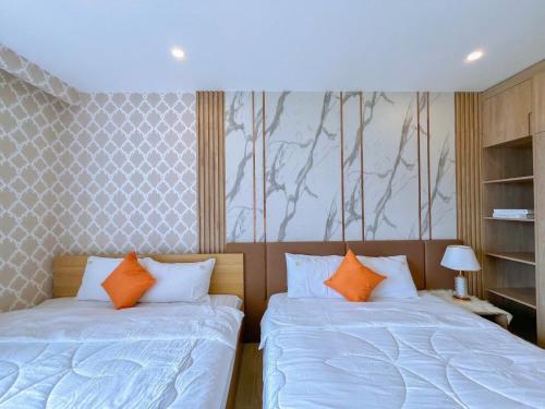 two beds with orange pillows in a bedroom at The Song Boutique Apartment in Vung Tau