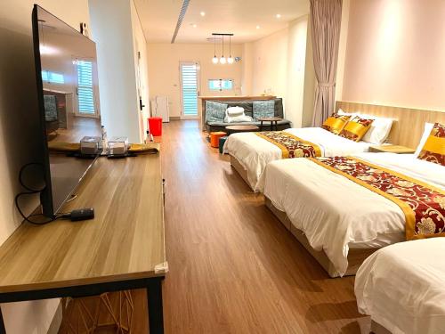 a hotel room with two beds and a flat screen tv at Daisy's Hsiang Hola in Chiayi City