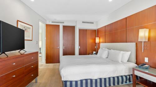 a hotel room with a bed and a flat screen tv at QV Stays Upscale Urban Sanctuary in Auckland