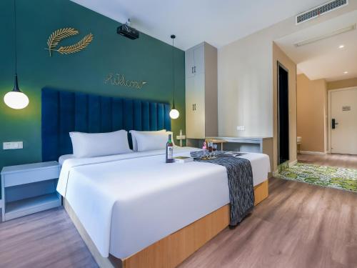 a bedroom with a large white bed and a blue wall at 重庆莎霏酒店大渡口店 in Chongqing