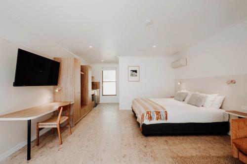 a bedroom with a bed and a desk and a tv at The Cudgee at Mudgee in Mudgee