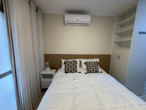 Un dormitorio con una cama blanca con dos almohadas. en Studio Céu de Brasília, en Brasilia