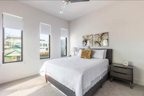 a white bedroom with a bed and two windows at Uptown Dallas Modern Retreat in Dallas