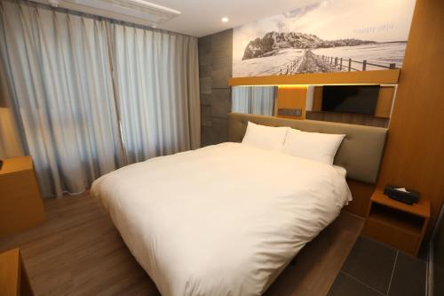 a bedroom with a large white bed and a television at Asia Jeju in Jeju