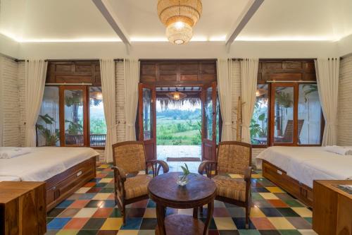 a bedroom with two beds and a table and chairs at Villa Sare - House with panorama rice field view in Yogyakarta