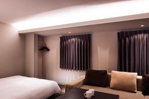 a hotel room with a bed and a couch at Rinn Sanjo Ohashi East in Kyoto