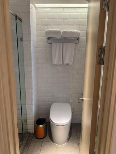 a bathroom with a toilet and a glass shower at Orange Beijing Yanqing Badaling Great Wall Hotel in Xibozi