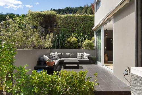 a patio with a couch on the side of a house at Central Sunset Charm in Queenstown